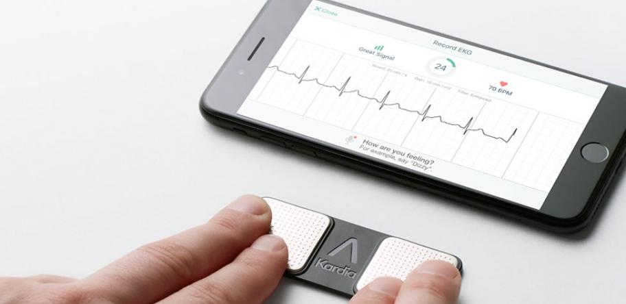 AliveCor monitor with person touching it with 2 fingers from each hand and smartphone showing ECG