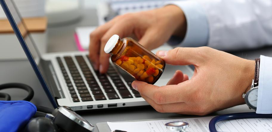 doctor looking up label on pill bottle on his computer