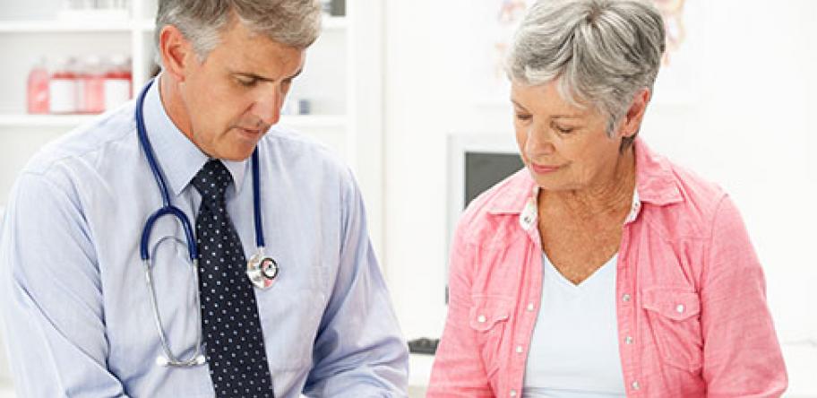 Male doctor talking to mature female patient